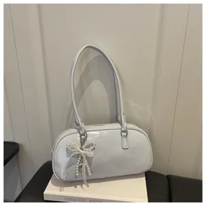 Vue détaillée d'un sac à main aisselle en cuir verni bleu clair avec pendentif nœud perlé.