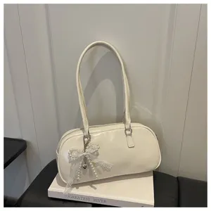 Vue détaillée du sac épaule blanc oreiller avec un élégant pendentif nœud en dentelle et perles.