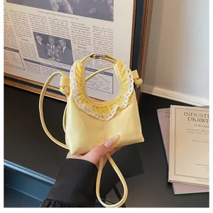 Detailed view of the trendy yellow mini crossbody moon bag with delicate lace trim.