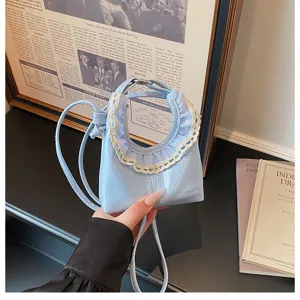 Close-up of trendy mini crescent crossbody bag featuring cute lace trim and smooth blue leather.