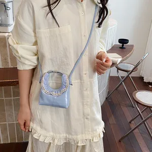 Light blue patent leather mini crescent crossbody bag with delicate lace trim for women.