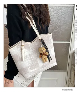 Detailed view of the casual checkered tote bag with cute bear pendant and strap, stylish design.