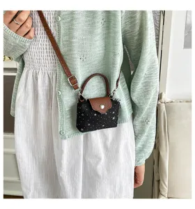 Mini cross-body bag detail showcasing star pattern fabric and brown leather handle strap.