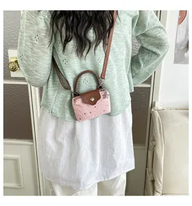 Chic mini crossbody handbag featuring pink star print fabric, brown handle and strap.