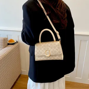 Bolso bandolera beige chic con motivo de monograma y herrajes dorados para uso diario.