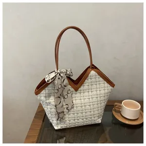 Detailweergave van stijlvolle tweed tote tas met V-vormige opening en zijden sjaal.