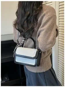 Vue détaillée d'un sac bandoulière chic bicolore avec un accessoire écharpe élégant porté.