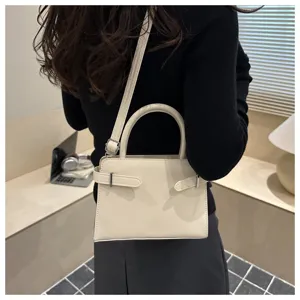Detail view of stylish beige shoulder bag with belt accent, showcasing premium texture and design.