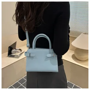 Light blue minimalist shoulder bag detail, elegant square design with metal buckle accents.