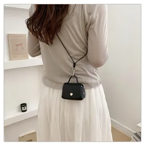 Detailopname van de zwarte mini crossbodytas, compact design met metalen drukknoopluit.