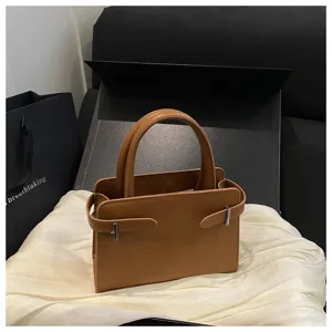 Chic brown leather handbag minimalist small square bag with top handle and metal strap design.