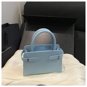Light blue minimalist handbag detail, stylish top handle small square bag with side strap.