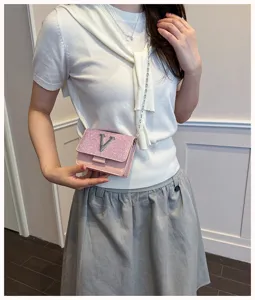 Vue détaillée élégante du sac bandoulière rose pailleté avec logo V en métal et chaîne.