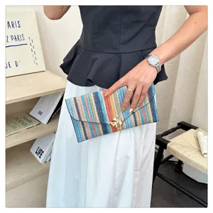 Close-up detail of the colorful striped woven envelope clutch bag, showing fine texture.