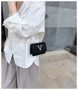 Gros plan détaillé d'un élégant mini sac bandoulière noir avec logo V et chaîne.