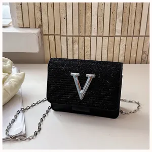 Vue détaillée du sac bandoulière noir pailleté avec chaîne et logo V en métal marquant.