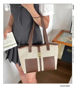 Detalle del bolso tote de lona con detalles de cuero marrón y elegante cierre metálico.