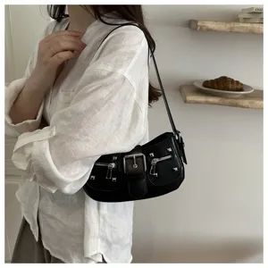 Dettaglio borsa a spalla retrò nera con borchie metalliche, fibbia frontale e tasche con zip chic.