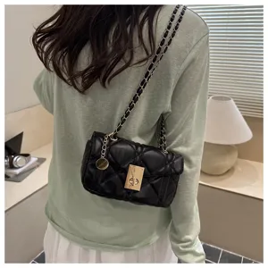 Detail shot of black quilted shoulder bag with chain strap and gold turn-lock closure.