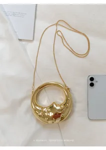 Gold crescent moon face crossbody bag detail, stylish metallic niche shoulder handbag.