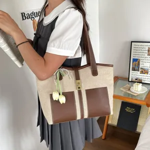 Vista detallada de elegante bolso tote de lona para viajero con ribete de cuero y abalorio de perla.