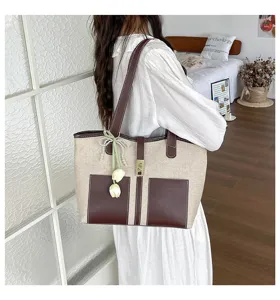 Detalle de bolso de lona con elegantes detalles en cuero marrón y cierre metálico.