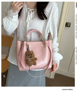 Pink PU leather bucket bag with cute bear charm, stylish single shoulder crossbody bag.