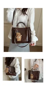 Detailed view of women's vintage brown leather bucket shoulder bag with cute plush bear pendant.