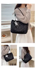 Detail shot of black canvas tote bag with silver star print and star charm, casual style.