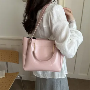 Detailed view of a stylish pink shoulder handbag worn by a model, showcasing minimalist design.