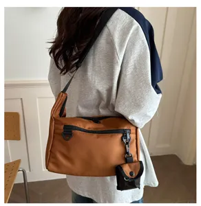 Close-up detail of casual brown messenger bag with small pouch, versatile crossbody style.