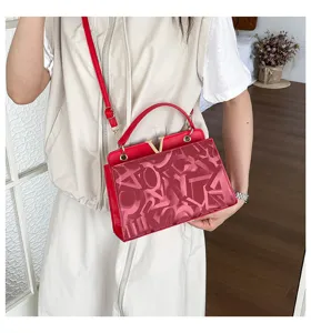 Red top-handle crossbody bag with metal V clasp and stylish monogram print for women.
