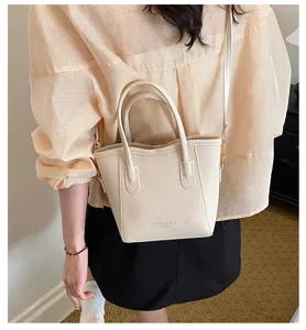 Chic minimalist faux leather bucket handbag with top handles and adjustable strap for women.