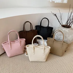 Detail view of multi-color leather bucket bags featuring pebbled texture and dual handles.