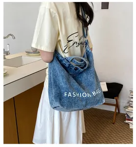 Detail shot of vintage denim hobo shoulder bag with large capacity and white letter print.
