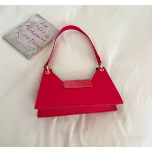 Exquisite pink trapezoid shoulder bag with stylish crocodile pattern flap and gold hardware rings.