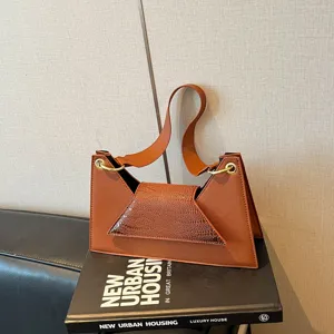 Detailed view of brown crocodile pattern crossbody bag with chic metallic ring accents.