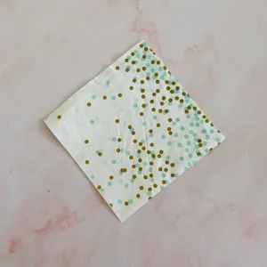 Close-up detail of disposable party paper napkin with green and gold polka dots pattern.