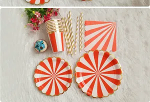 Detailed shot of gold-stamped orange striped disposable paper plates, cups and straws for party.