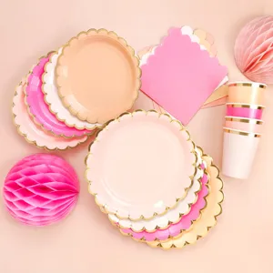 Detailansicht von rosa und pfirsichfarbenen Papptellern mit Goldrand sowie Partydeko.