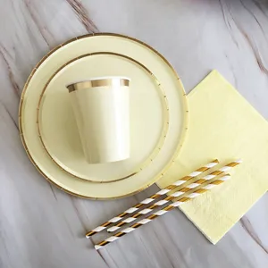 Detailed shot of disposable yellow paper plates, gold rim cups, napkins and striped straws.