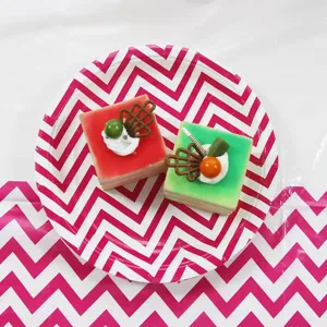 Detailed view of disposable party paper plate with pink chevron pattern and mini cake decor.