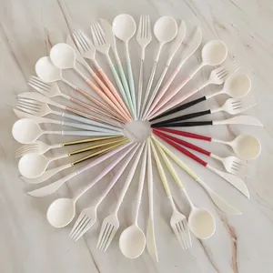 Colorful handle plastic cutlery detail showing spoon fork knife set on marble surface.