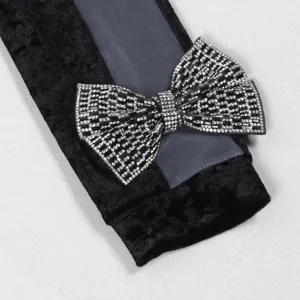 Close-up view of a black velvet sleeve featuring sparkling rhinestone bow and mesh patchwork.