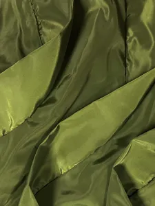 Close-up detail of glossy olive green satin fabric showing rich texture and elegant drape.