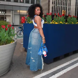 Street fashion denim maxi skirt detail shot, high waist distressed raw edge styling.