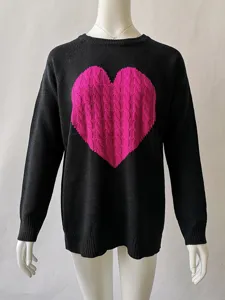 Detailaufnahme schwarzer Strickpullover mit pinkem Zopfstrick Herz Motiv und Rundhalsausschnitt.