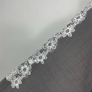 Detail of women's elegant gray dress featuring exquisite white floral sequin lace trim.