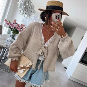 Vista dettagliata del cardigan in maglia da donna con fiocco in un ambiente interno moderno.