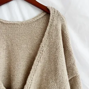 Ravvicinato dettaglio del cardigan con lavorazione a maglia grossa in tinta beige.